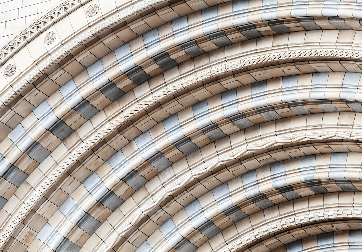 Closeup of curved stone entry way to a building with ivory and grey stone
